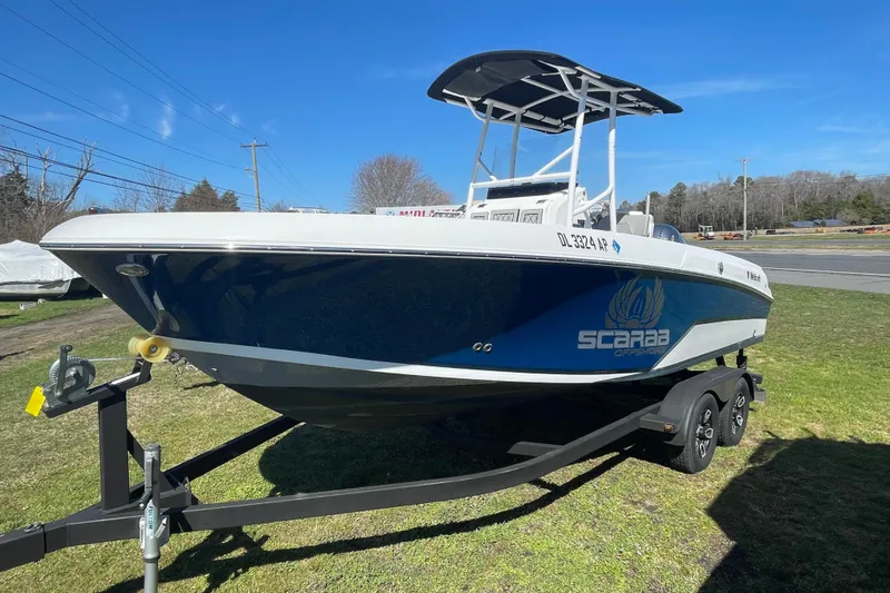 Slide: The Image of 2022 Wellcraft 202 Fisherman boat on trailer, blue and white design, parked on grass. - 13