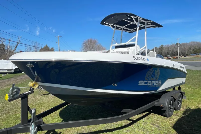 Slide: The Image of 2022 Wellcraft 202 Fisherman boat on trailer, blue and white design, parked on grass. - 14