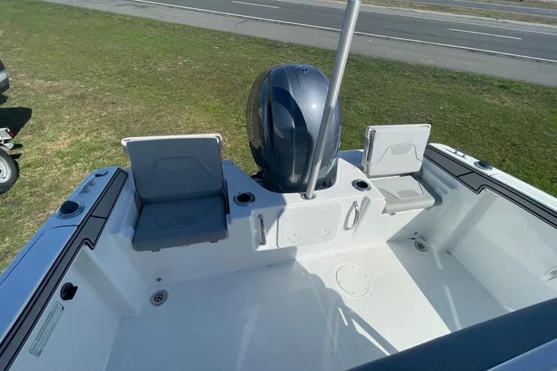 Slide: The Image of 2022 Wellcraft 202 Fisherman boat interior with seating and motor, parked on grass. - 19