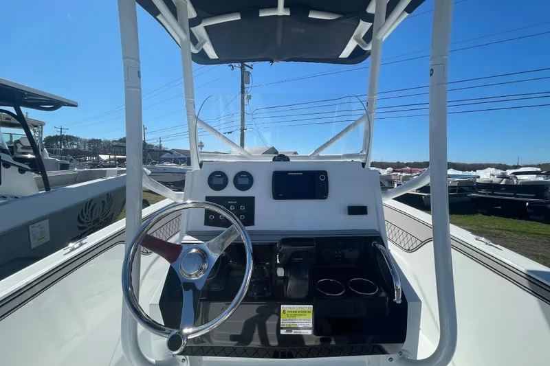 Slide: The Image of 2022 Wellcraft 202 Fisherman boat dashboard with steering wheel and controls under clear blue sky. - 21