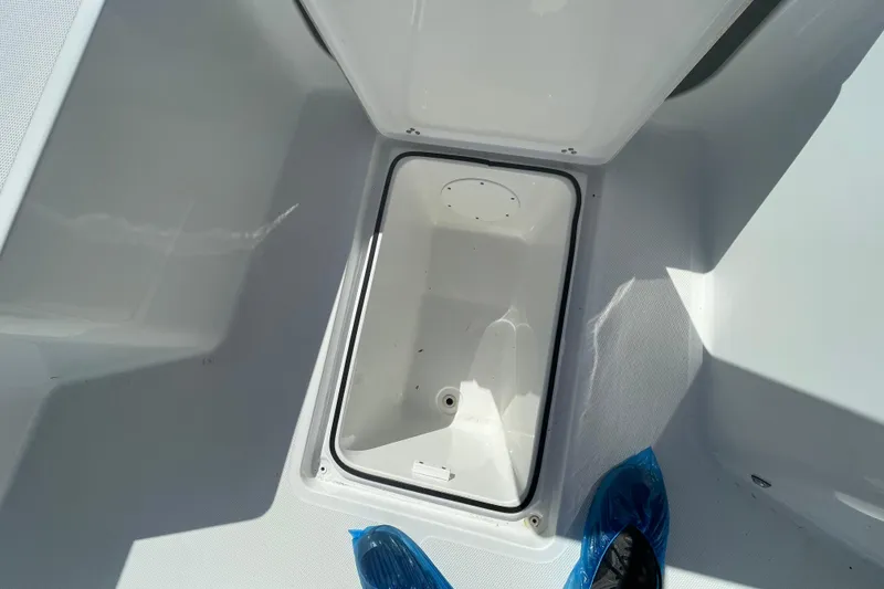 Slide: The Image of 2022 Wellcraft 202 Fisherman storage compartment, open lid, white interior, blue shoe covers visible. - 3