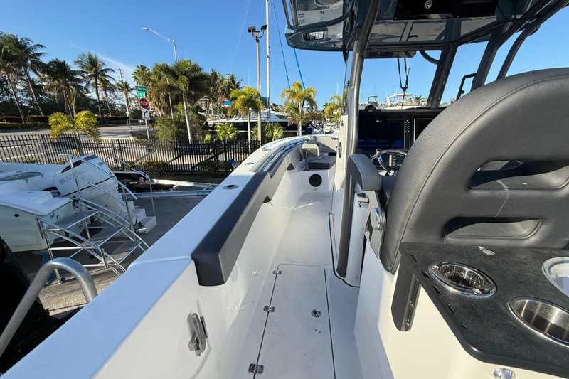 Slide: The Image of 2026 Sea Pro 292 DLX boat interior with seating and cup holders, surrounded by palm trees. - 16