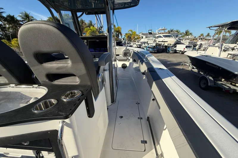 Slide: The Image of 2026 Sea Pro 292 DLX boat interior with seating and cup holders, docked in a marina. - 21