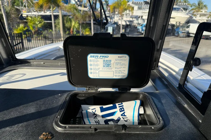 Slide: The Image of 2026 Sea Pro 292 DLX boat dashboard with open storage compartment and instruction label. - 22