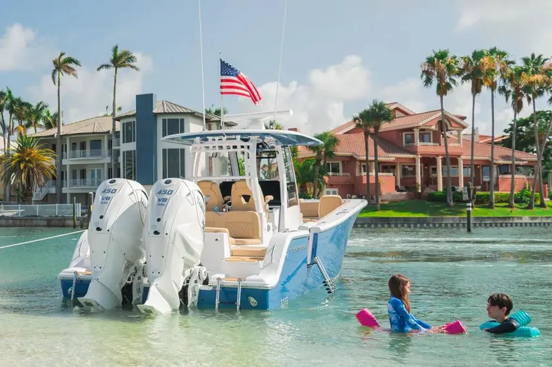 Slide: The Image of Manufacturer Provided Image: 2025 Sportsman Heritage 321 Center Console boat near waterfront homes, with people swimming nearby. - 1