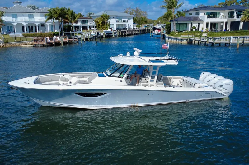 The Image of 2022 Pursuit S 428 Sport boat cruising in a scenic waterfront neighborhood. - 0