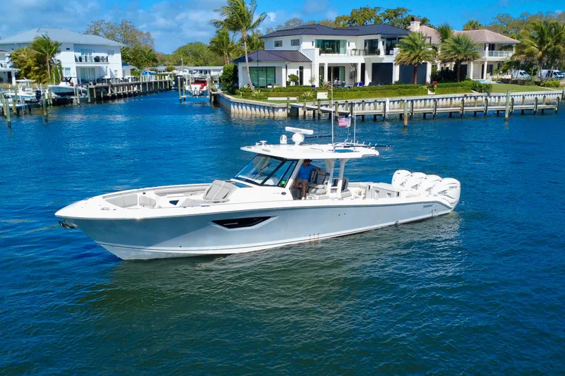 Slide: The Image of 2022 Pursuit S 428 Sport boat cruising near waterfront homes. - 2