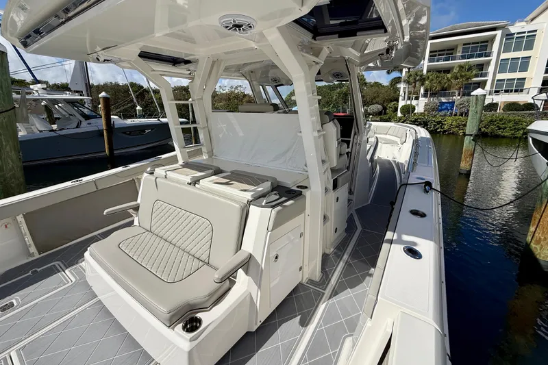 Slide: The Image of 2022 Pursuit S 428 Sport boat interior with seating, docked near waterfront buildings. - 32