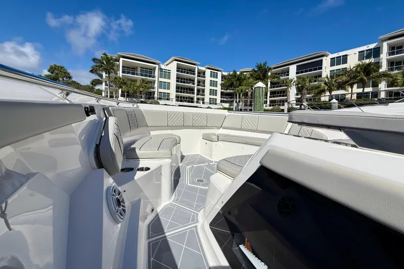 Slide: The Image of 2022 Pursuit S 428 Sport boat interior with luxurious seating, docked near modern buildings. - 46
