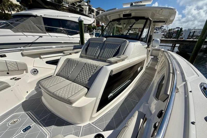 Slide: The Image of 2022 Pursuit S 428 Sport boat with luxurious seating and sleek design at a marina. - 50