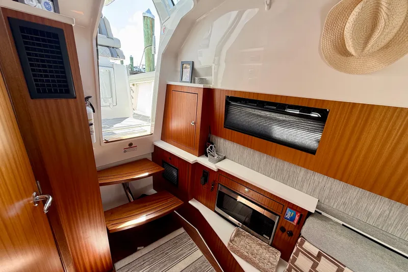 Slide: The Image of 2022 Pursuit S 428 Sport cabin interior with wood finish, microwave, and seating area. - 56