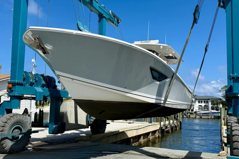 Slide: The Image of 2022 Pursuit S 428 Sport boat being lifted at a marina under clear blue skies. - 61