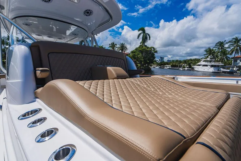 Slide: The Image of 2023 Valhalla Boatworks V-46 with luxurious tan seating, docked by palm trees and yachts. - 28