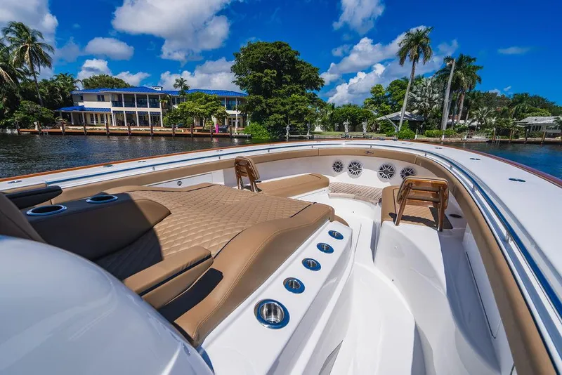 Slide: The Image of 2023 Valhalla Boatworks V-46 luxury deck with seating, docked by waterfront homes, under blue skies. - 29