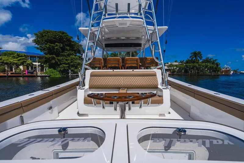 Slide: The Image of 2023 Valhalla Boatworks V-46 luxury yacht interior with seating and table, docked by lush greenery. - 32