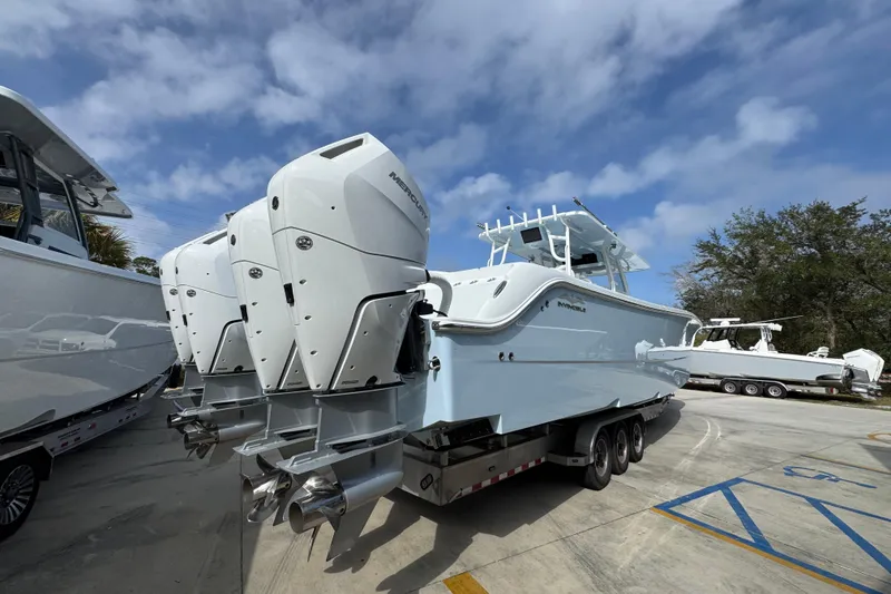 Slide: The Image of 2026 Invincible 46 Catamaran with powerful outboard engines, parked on a trailer under a blue sky. - 11