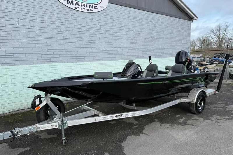 The Image of 2026 Xpress H18 boat on trailer, black with green accents, parked outside marine shop. - 0