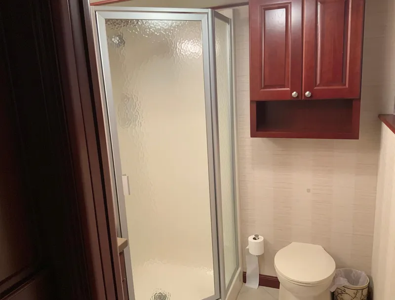 Slide: The Image of Bathroom in 2007 Skipperliner 640 with shower, toilet, and wooden cabinets. - 44