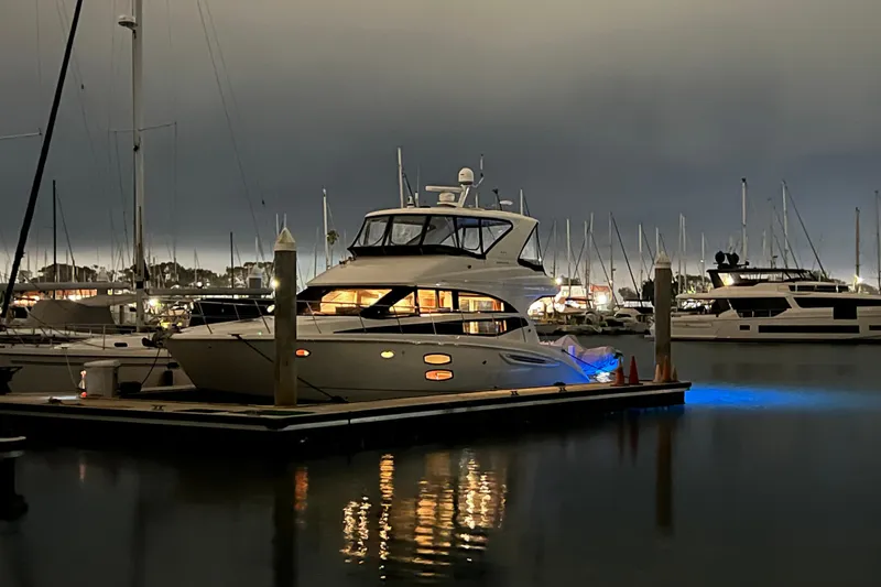 Slide: The Image of 2013 Meridian 441 Sedan yacht docked at marina during evening, illuminated with blue lights. - 2
