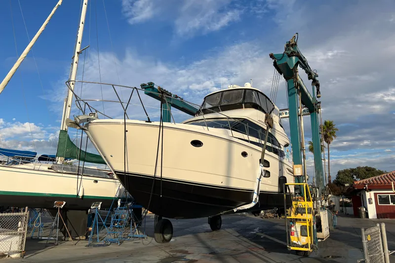 Slide: The Image of 2013 Meridian 441 Sedan yacht lifted in a boatyard under a blue sky. - 52