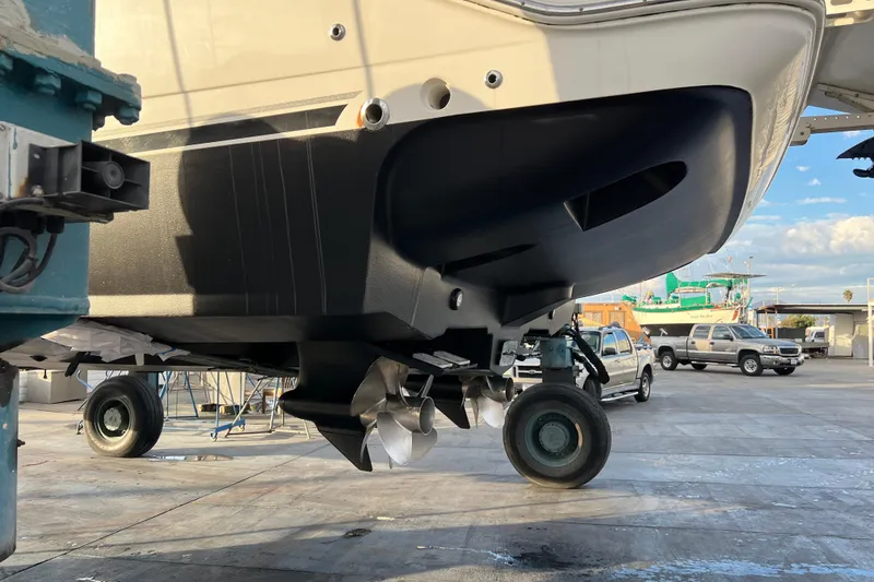 Slide: The Image of 2013 Meridian 441 Sedan yacht on trailer, showcasing propellers and hull in a boatyard setting. - 54