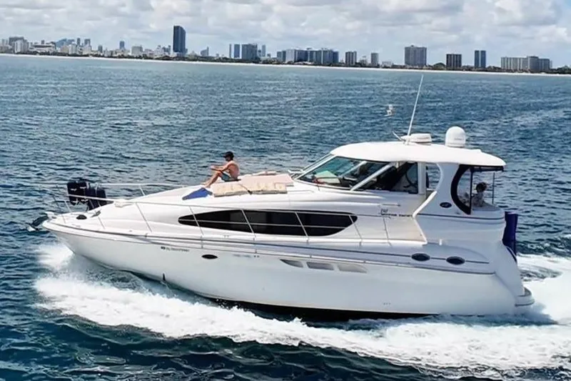 Slide: The Image of 2003 Sea Ray 390 Motor Yacht cruising on open water with city skyline backdrop. - 0