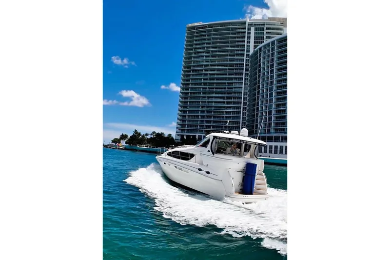 Slide: The Image of 2003 Sea Ray 390 Motor Yacht cruising near modern high-rise buildings. - 2