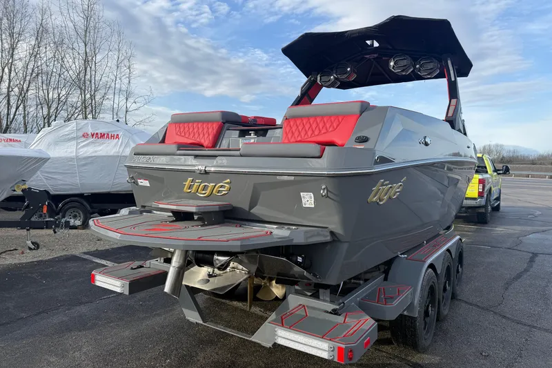 Slide: The Image of 2026 Tigé 24RZX boat with red accents on a trailer, parked outdoors. - 6