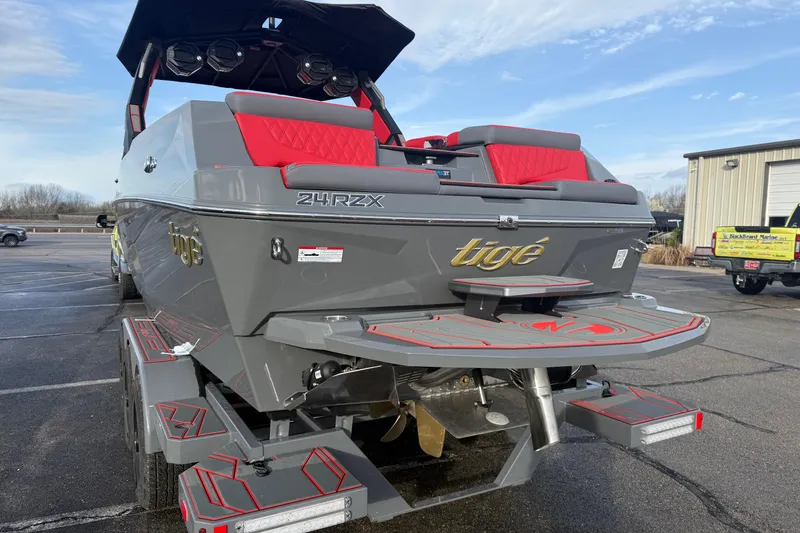 Slide: The Image of 2026 Tigé 24RZX boat with sleek gray design and red accents, parked outdoors. - 8