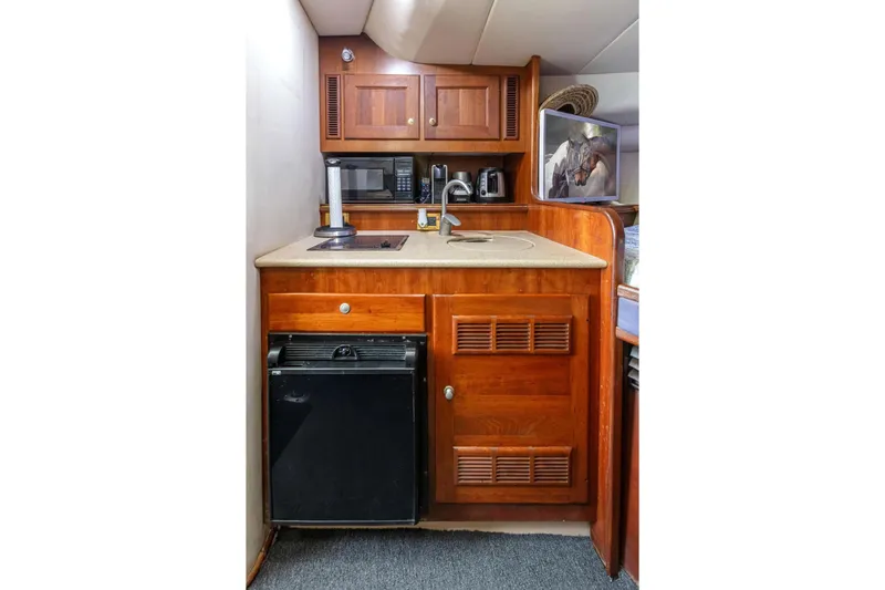 Slide: The Image of Compact kitchen area in a 2000 Rampage 30 Express boat with wooden cabinetry and appliances. - 14