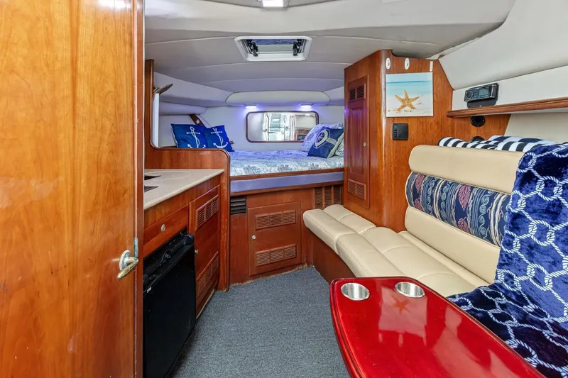 Slide: The Image of Cozy interior of 2000 Rampage 30 Express boat with bed, seating, and wooden cabinetry. - 16