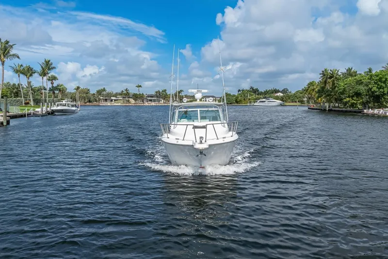 Slide: The Image of 2000 Rampage 30 Express boat cruising on a scenic waterway with palm trees. - 8