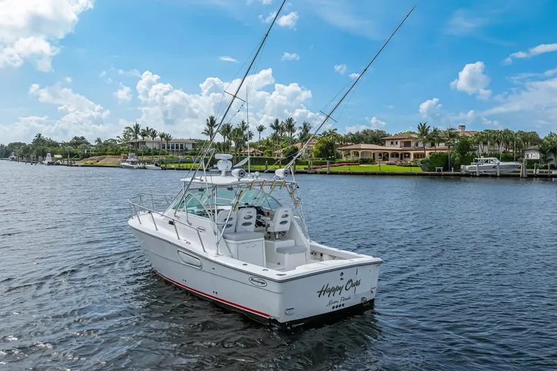 Slide: The Image of 2000 Rampage 30 Express boat on water, luxury homes in background, clear sky. - 9