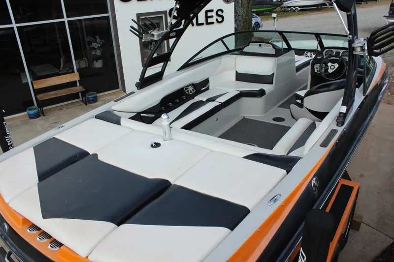 Slide: The Image of 2012 Moomba Mojo 2.5 boat interior with black and white seating, docked near a sales office. - 10