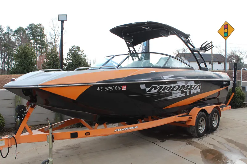 Slide: The Image of 2012 Moomba Mojo 2.5 boat on trailer, black and orange design, parked outdoors. - 8