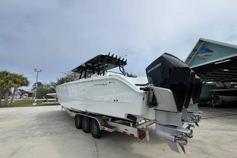 Slide: The Image of 2026 Invincible 38 Catamaran with Mercury engines on a trailer, parked outdoors. - 16