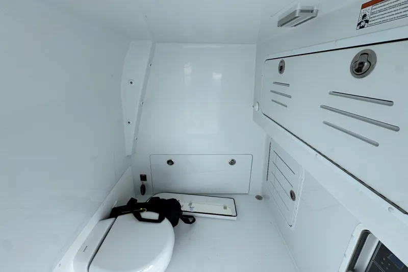 Slide: The Image of Interior of 2026 Invincible 38 Catamaran, featuring a compact marine toilet and storage compartments. - 28