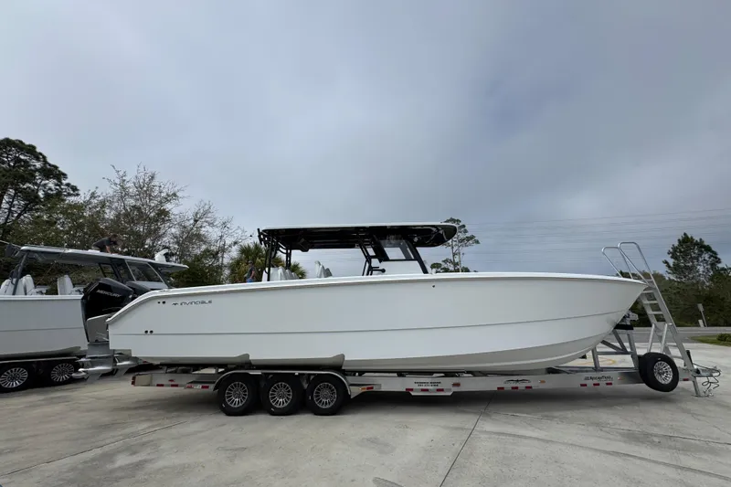 Slide: The Image of 2026 Invincible 38 Catamaran on trailer, parked outdoors under cloudy sky. - 9