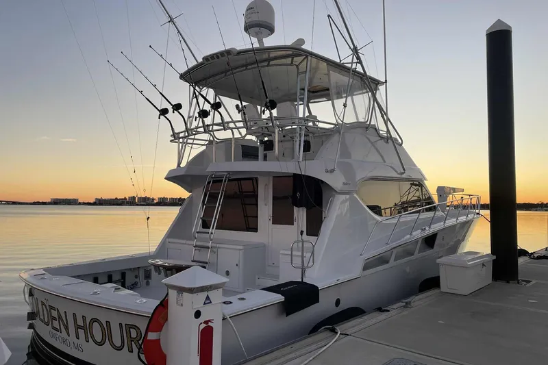 The Image of 2002 Hatteras 55 Convertible yacht docked at sunset, featuring fishing equipment. - 0