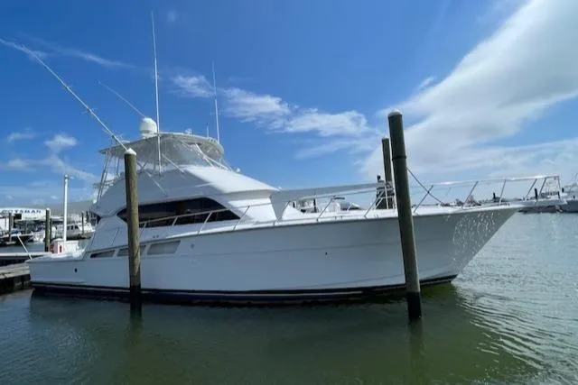 Slide: The Image of 2002 Hatteras 55 Convertible yacht docked in marina under clear blue sky. - 2