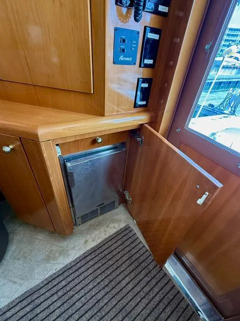 Slide: The Image of Interior of 2002 Hatteras 55 Convertible yacht with open wooden cabinet and control panel. - 43