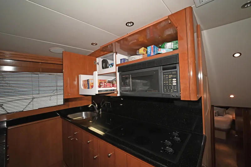 Slide: The Image of Kitchen area of 2002 Hatteras 55 Convertible yacht with microwave and open cabinets. - 58