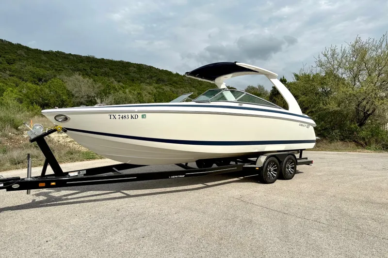 Slide: The Image of 2005 Cobalt 262 boat on trailer, parked outdoors with trees in background. - 10