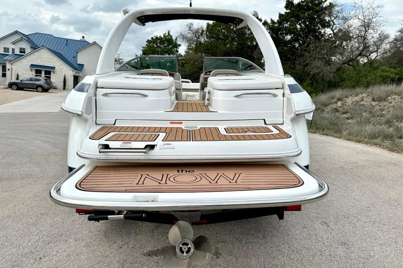 Slide: The Image of 2005 Cobalt 262 boat with teak swim platform, parked on a driveway near a house. - 13