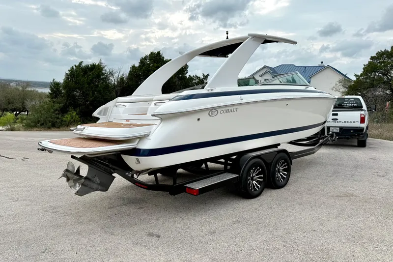 Slide: The Image of 2005 Cobalt 262 boat on trailer, parked outdoors with cloudy sky backdrop. - 14