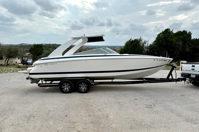 Slide: The Image of 2005 Cobalt 262 boat on trailer, parked outdoors under cloudy sky. - 15