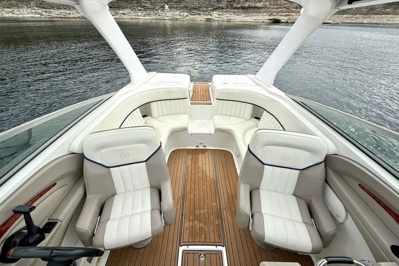 Slide: The Image of 2005 Cobalt 262 boat interior with white seating and wooden flooring on a lake. - 21
