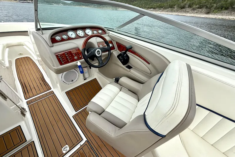 Slide: The Image of 2005 Cobalt 262 boat interior with wood accents and steering wheel on a lake. - 22
