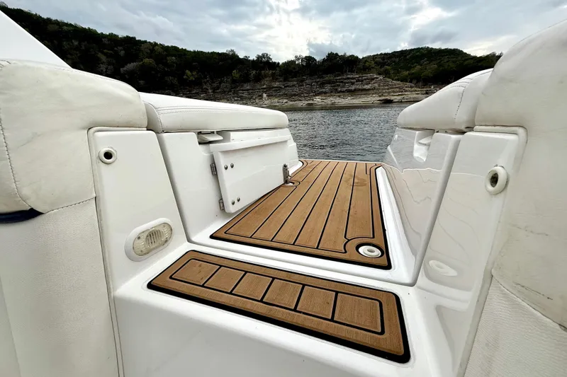 Slide: The Image of 2005 Cobalt 262 boat deck with teak flooring, overlooking a scenic lake and forested hills. - 26