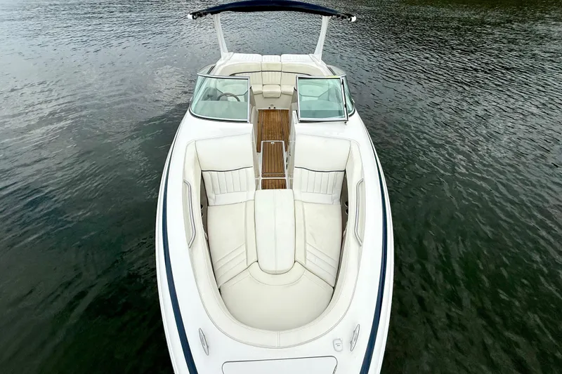 Slide: The Image of 2005 Cobalt 262 boat with white seating and wooden deck on calm water. - 29